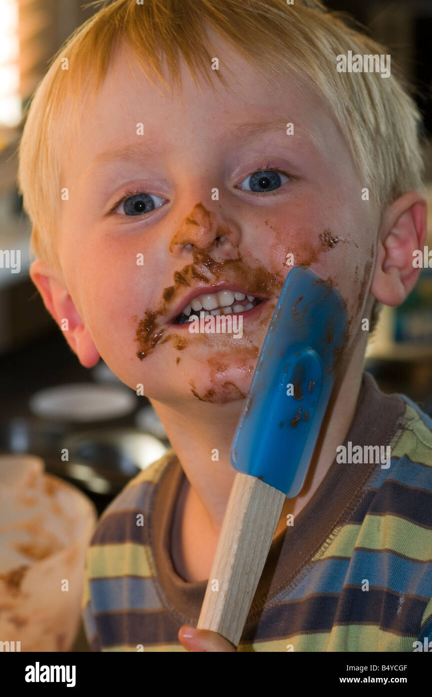 Boy with chocolate covered mouth holding spatula Stock Photo