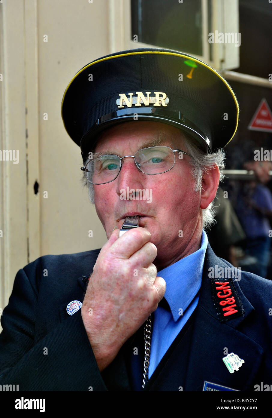 train guard on North Norfolk railway blowing departure whistle on