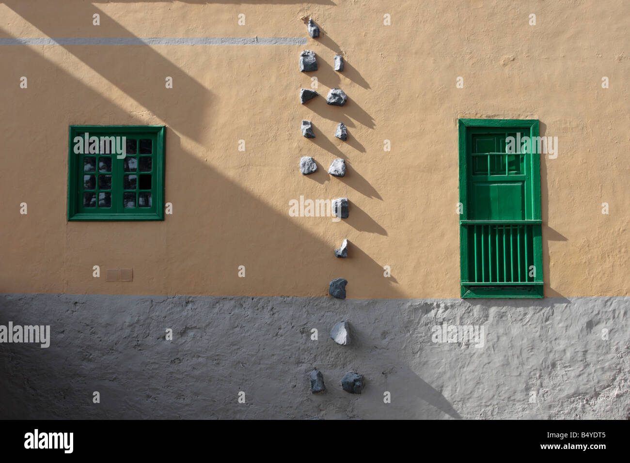 Wall with typical style of window and shutters and stones embedded on side of house in Guia de Isora, Tenerife Stock Photo