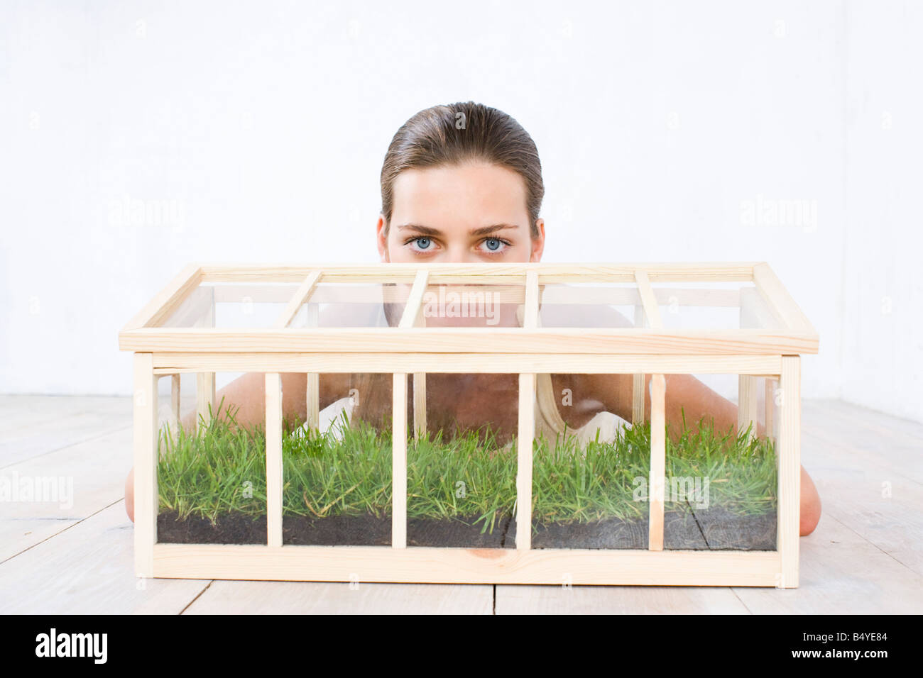 young woman raising grass in small glasshouse Stock Photo