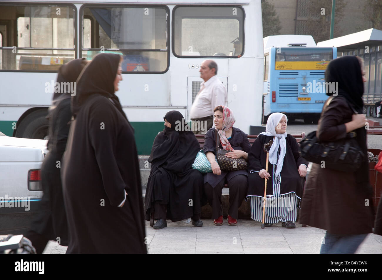 Three Women with different styles of outfits and Hijabs (Islamic dress) sitting on a bench in Tajrish, North of Tehran Stock Photo