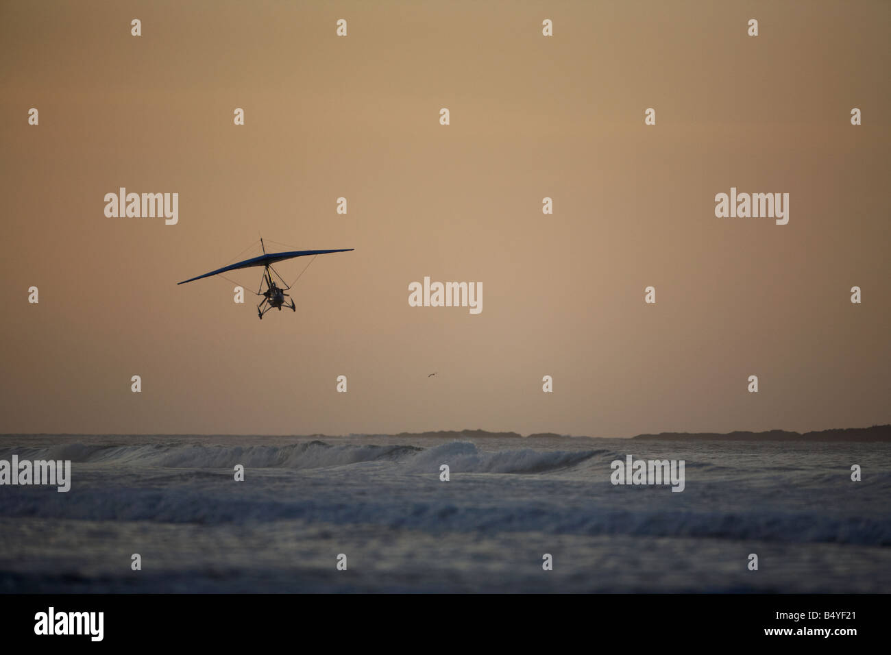microlite flying over the sea at white rocks beach in portrush at sunset northern ireland Stock Photo