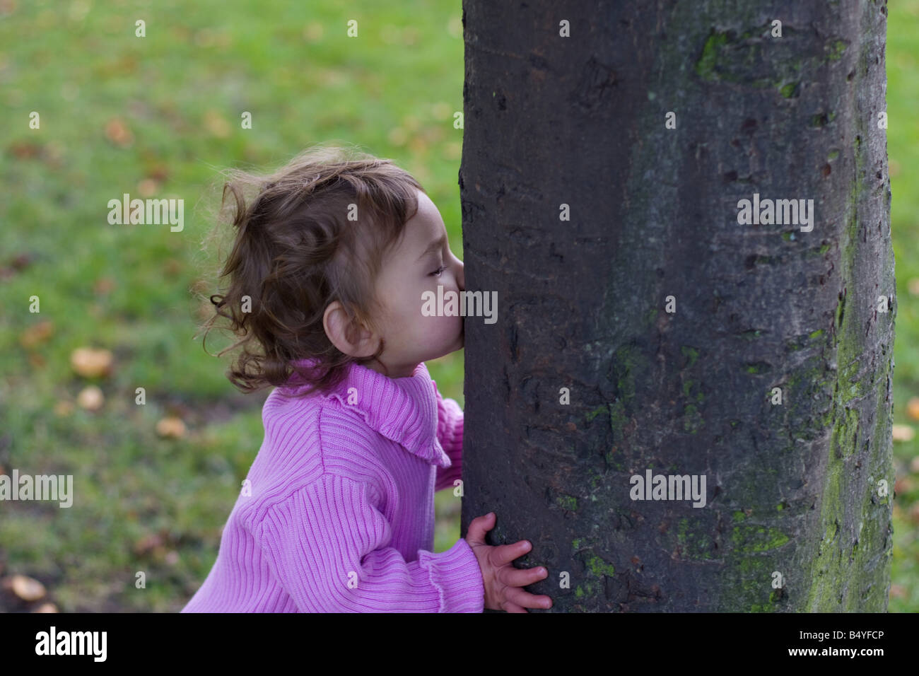 baby toddler child kissing a tree at park London Clapham common Battersea Lambeth Wandsworth Stock Photo