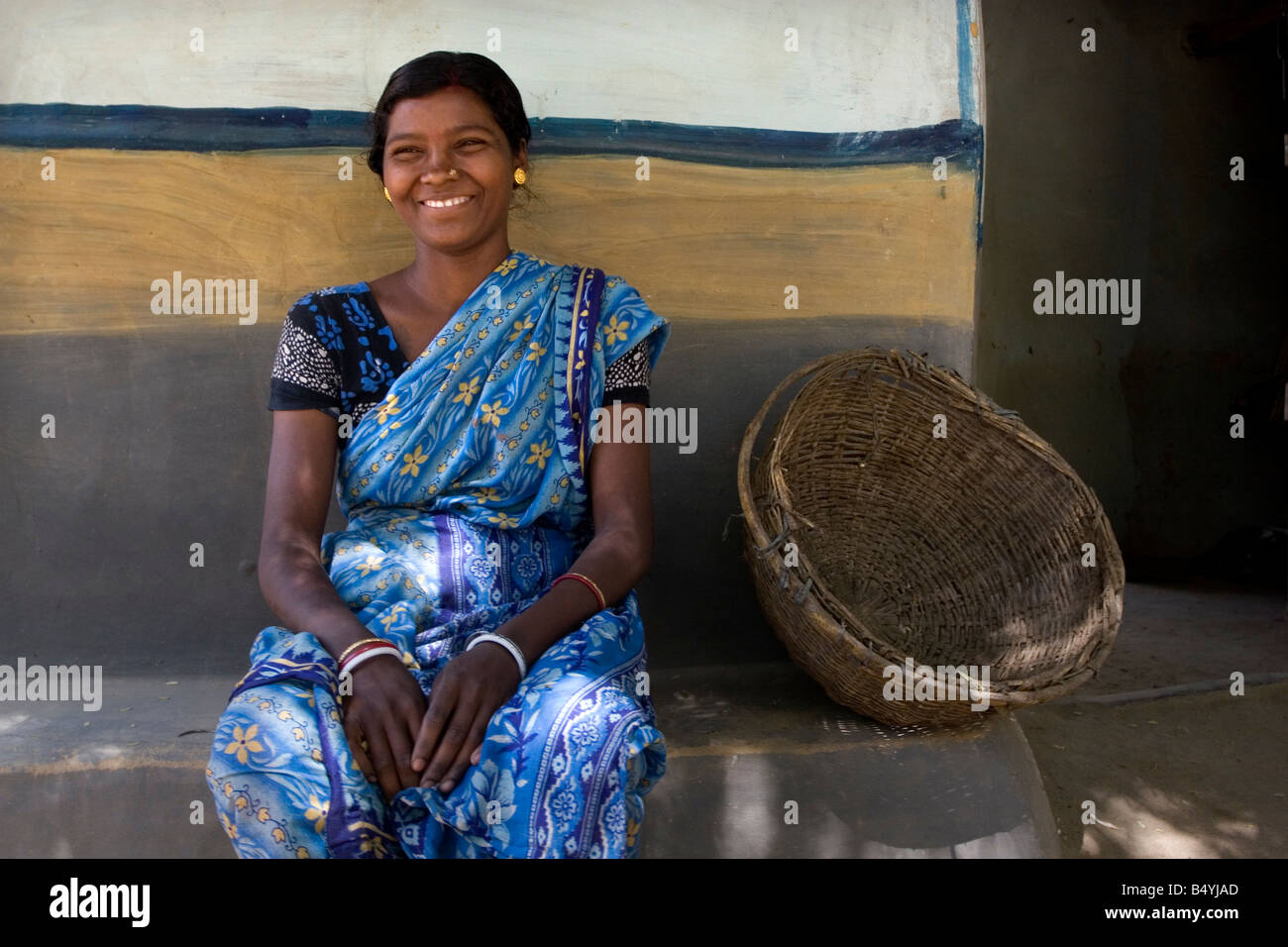 A village tribal woman sitting in front of an earthen house at remote ...