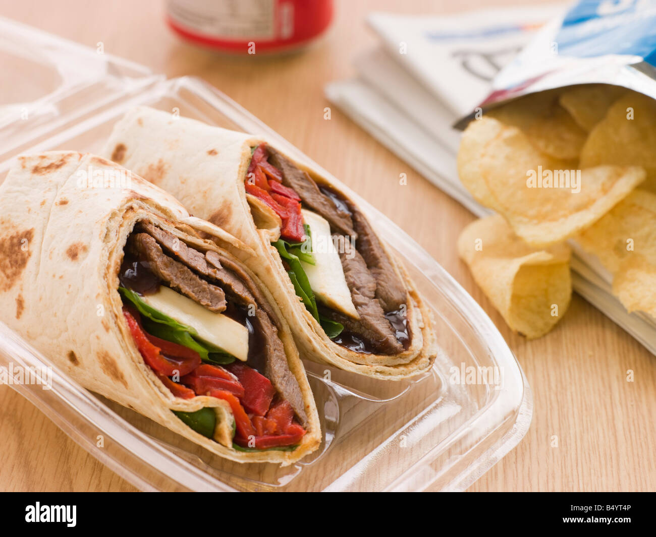 Steak, Cheese, Red Pepper And Barbeque Sauce Tortilla Wrap With A Can Of Cola And Packet Of Crisps Stock Photo