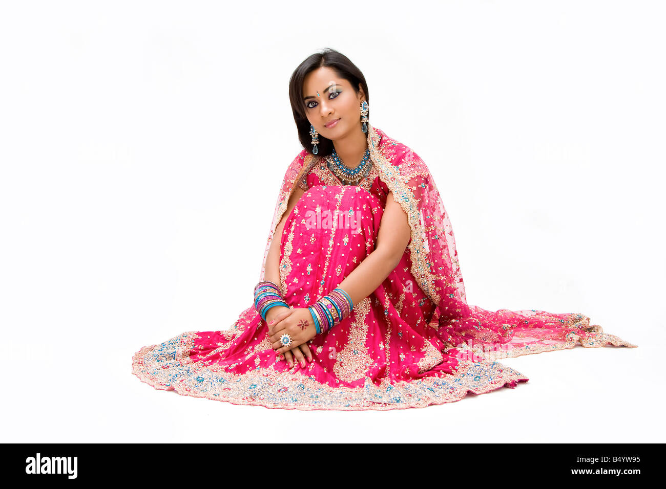 Beautiful Bangali bride in colorful dress sitting isolated Stock Photo