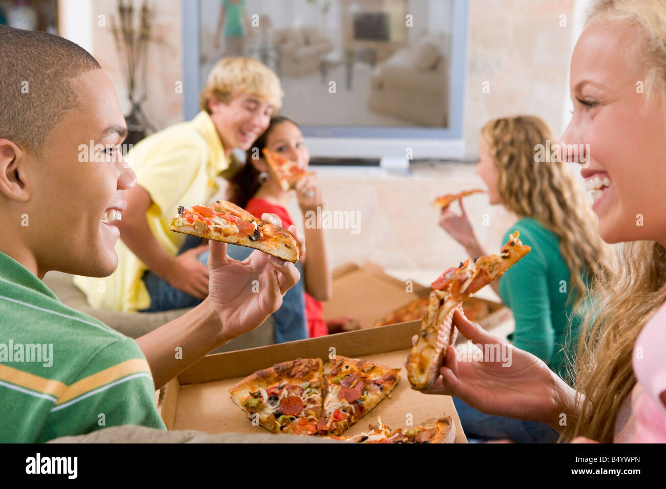 Teenagers Hanging Out In Front Of Television Eating Pizza Stock Photo