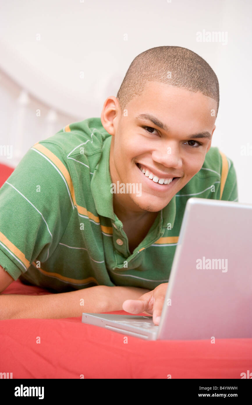 Teenage Boy Lying On Bed Using Laptop Stock Photo - Alamy