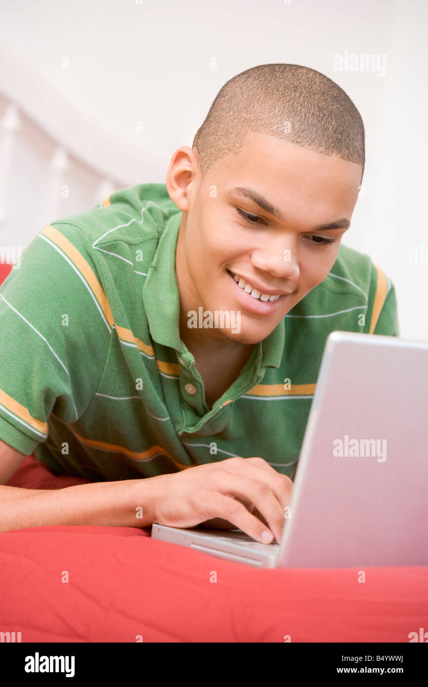 Teenage Boy Lying On Bed Using Laptop Stock Photo - Alamy