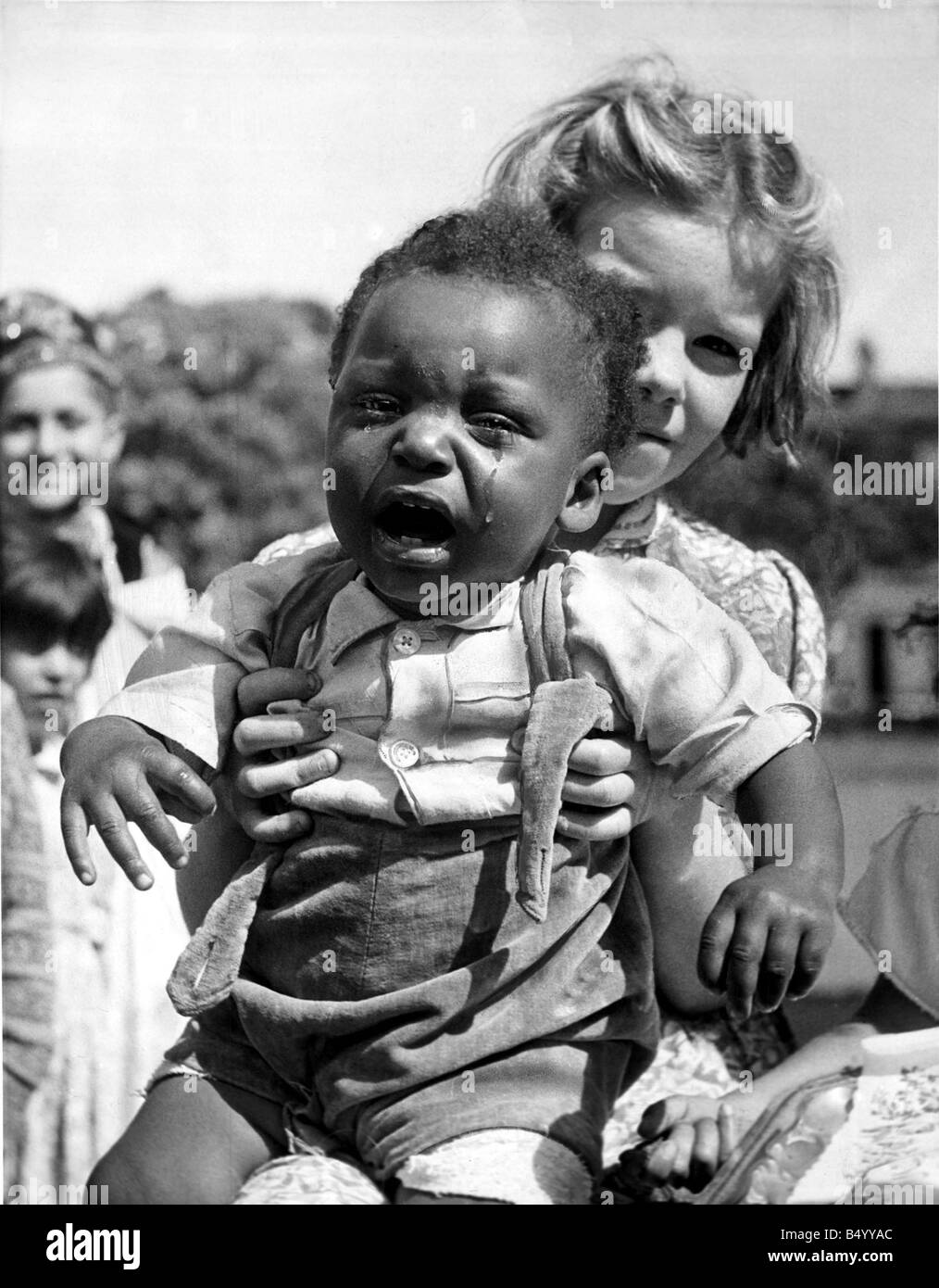 A Baby crying being held by a young girl at a festival tea party July 1953 Stock Photo