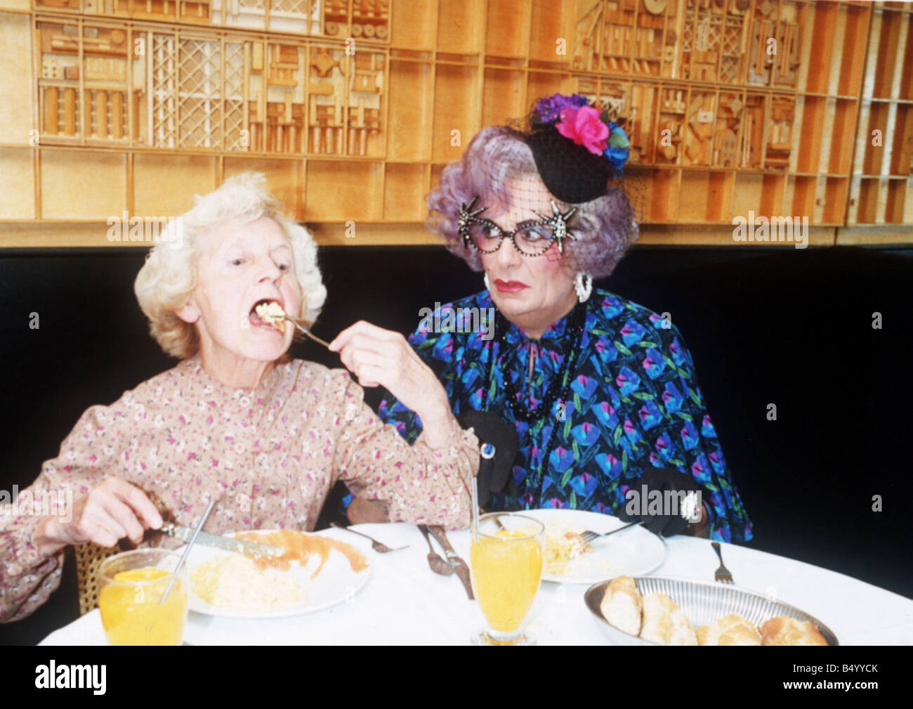 Barry Humphries as Dame Edna Everage glasses hat with Madge open mouth eating in La Caprice restaurant Stock Photo