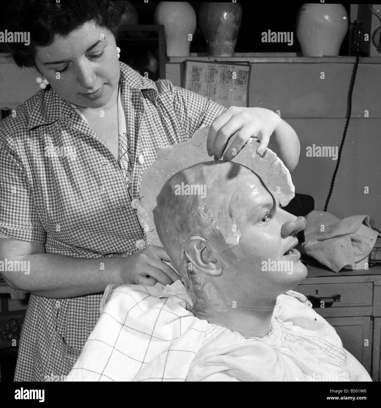 Comedian Benny Hill having a plaster cast of his skull made, so a wig can be correctly fitted. Hill can be seen wearing a false Stock Photo