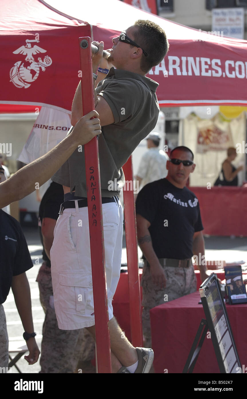 Visitors to a US Marine Corps recruiting booth at a street fair demonstrate their pull up abilities Stock Photo