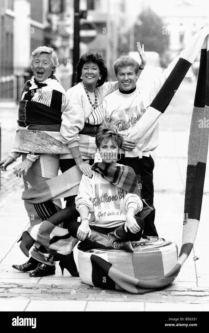 Lulu pop singer sitting on a 15 mile scarf being knitted all over the country by residents of the Abbeyfield homes hoped to be 20 miles long by the start of the Telethon Also standing wrapped in the scarf are Michael Aspel presenter TV and radio Cilla Black singer and TV presenter of Blind Date and Chris Quinten presenter Stock Photo