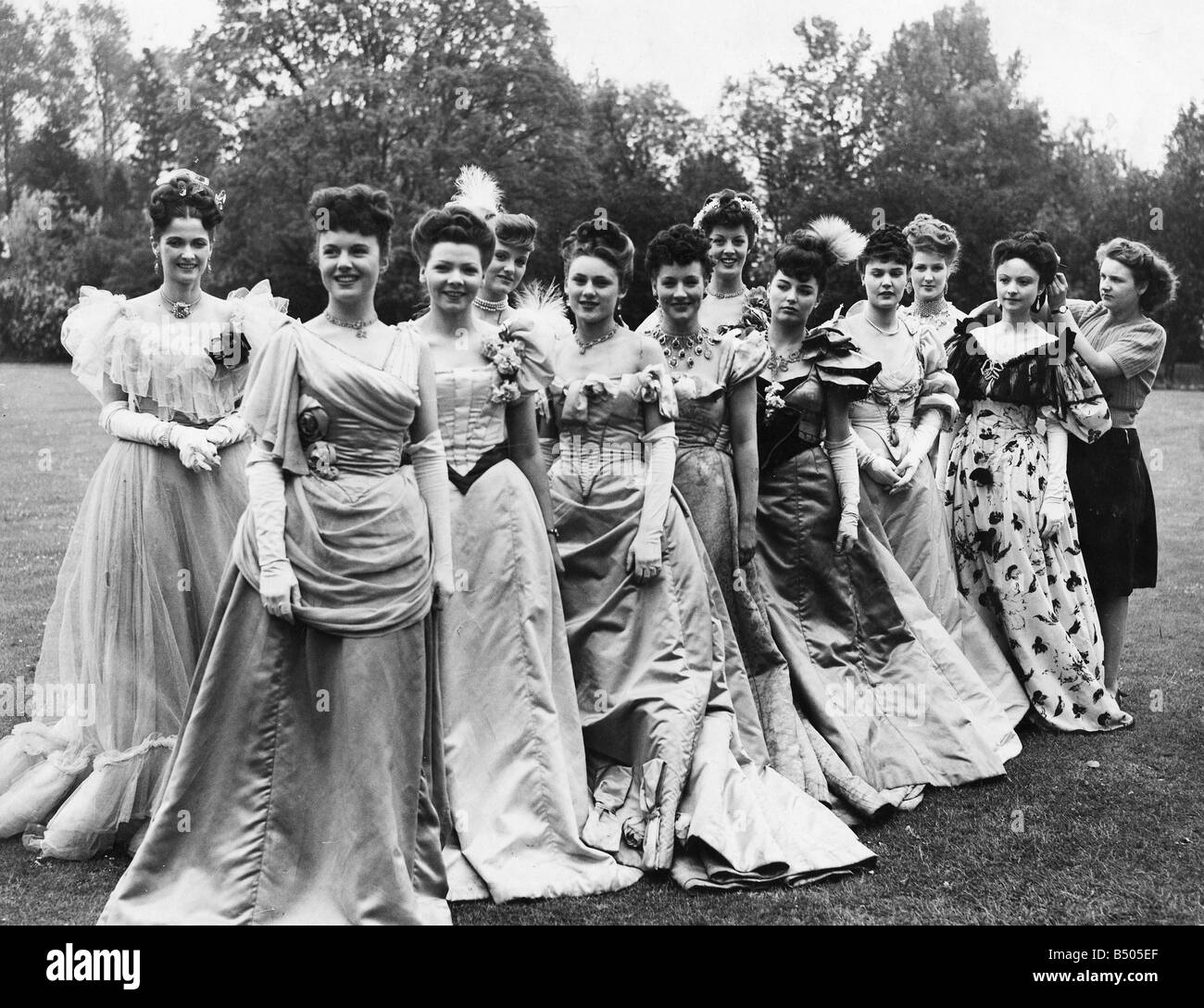Just after dawn on the lawn of Shepperton Studios, first parade ;Its not all fun being in films. These show girls all with different hair styles, have to be on parade at Shepperton Studio looking glamourous and with hair perfect at 7am for their part in Sir Alexander Korda's new film 'An Ideal Husband'.;Here they are on hair dressing parade having a final look over by the hairdresser before they go on set.;May 1947 Stock Photo