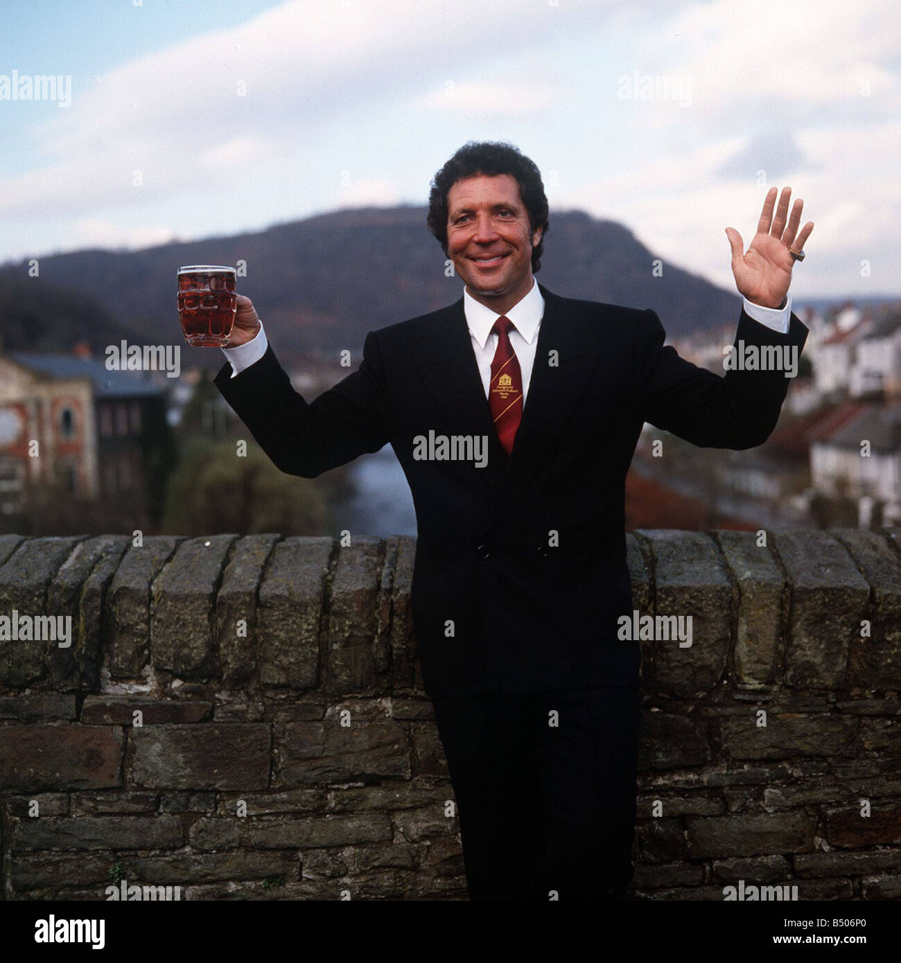 Tom Jones Singer in his home town in Wales standing by brick wall holding pint glass of beer Stock Photo