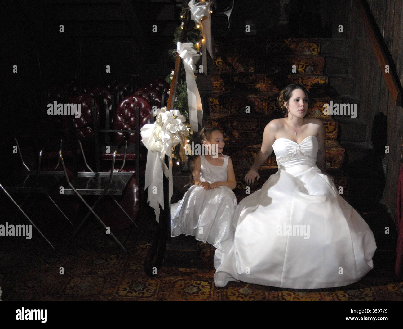 A flower girl and bride sit on stairs following a wedding Stock Photo