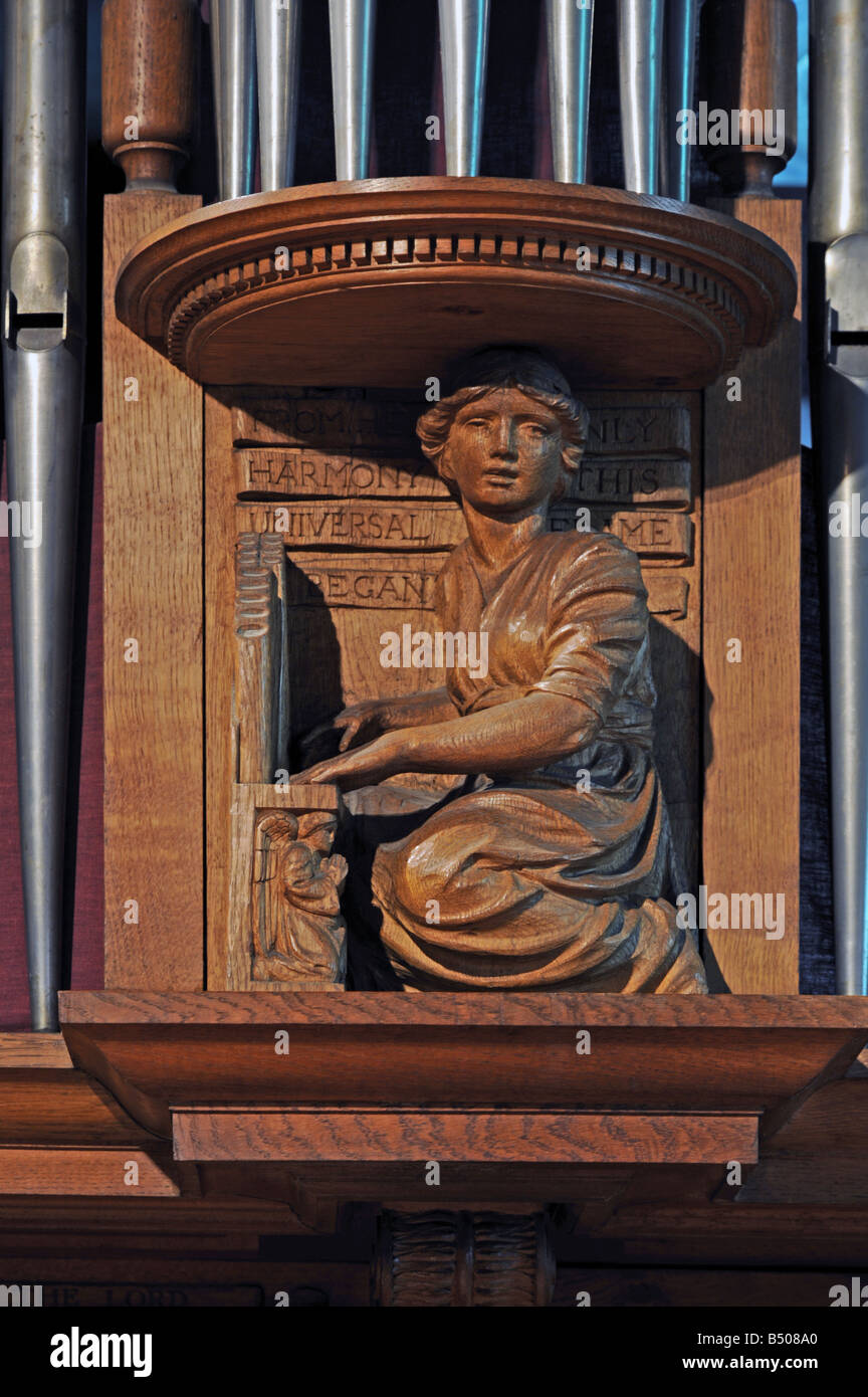 Girl playing organ. Wooden carving on organ case. Church of Saint Mary and Saint Michael, Great Urswick, Cumbria, England. Stock Photo