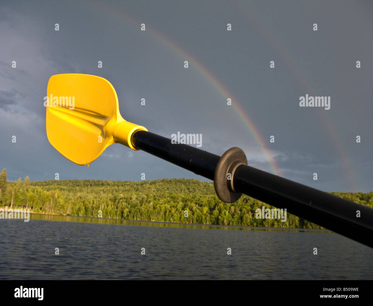 Rainbow with yellow kayak paddle with water droplets in New Brunswick, Canada Stock Photo