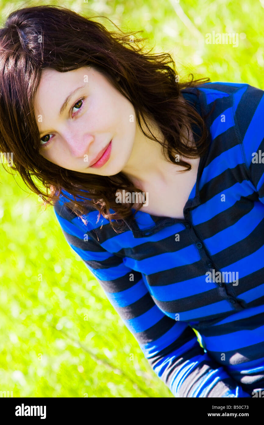 Smiling young girl staring at camera over green background Stock Photo