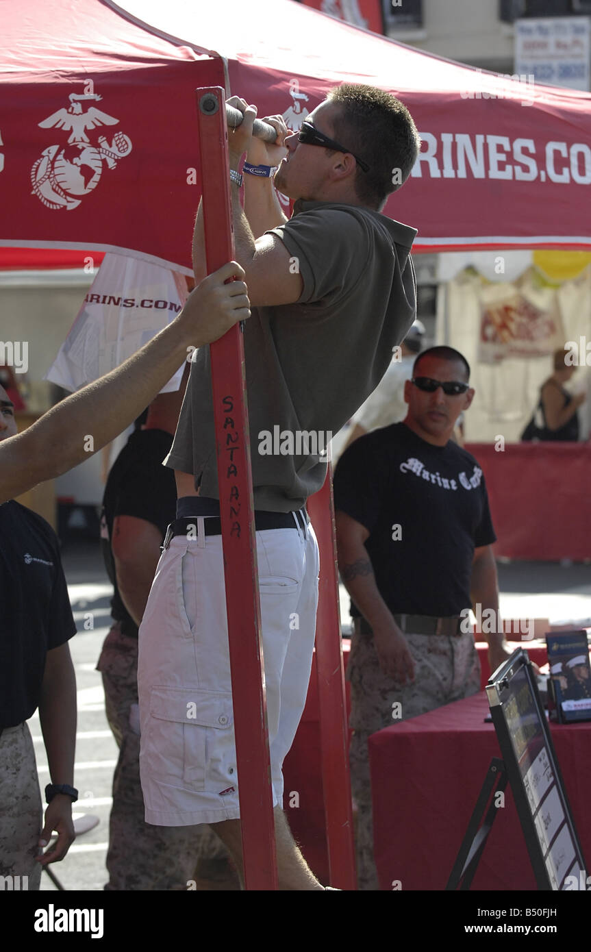 Visitors to a US Marine Corps recruiting booth at a street fair demonstrate their pull up abilities Stock Photo