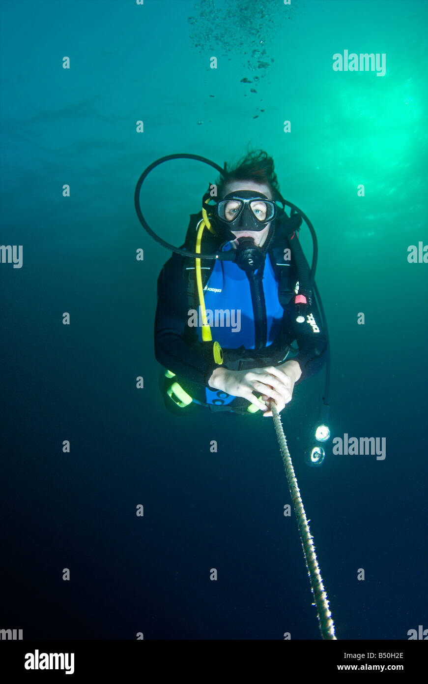 Scuba diver on line underwater with sea surface above Stock Photo