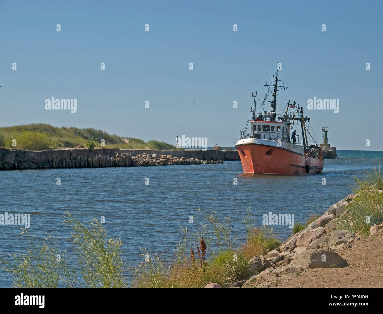 old fishing boat coming in canal to wharf at port Liepaja  Baltic Sea in Pavilosta Latvia Baltic states Stock Photo