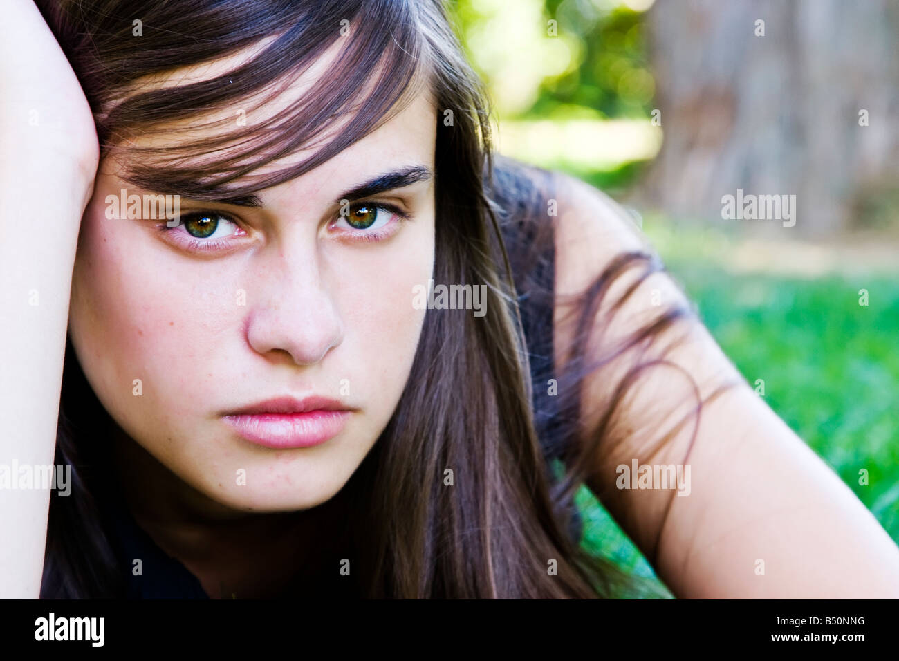 Young staring woman laying on the grass Stock Photo