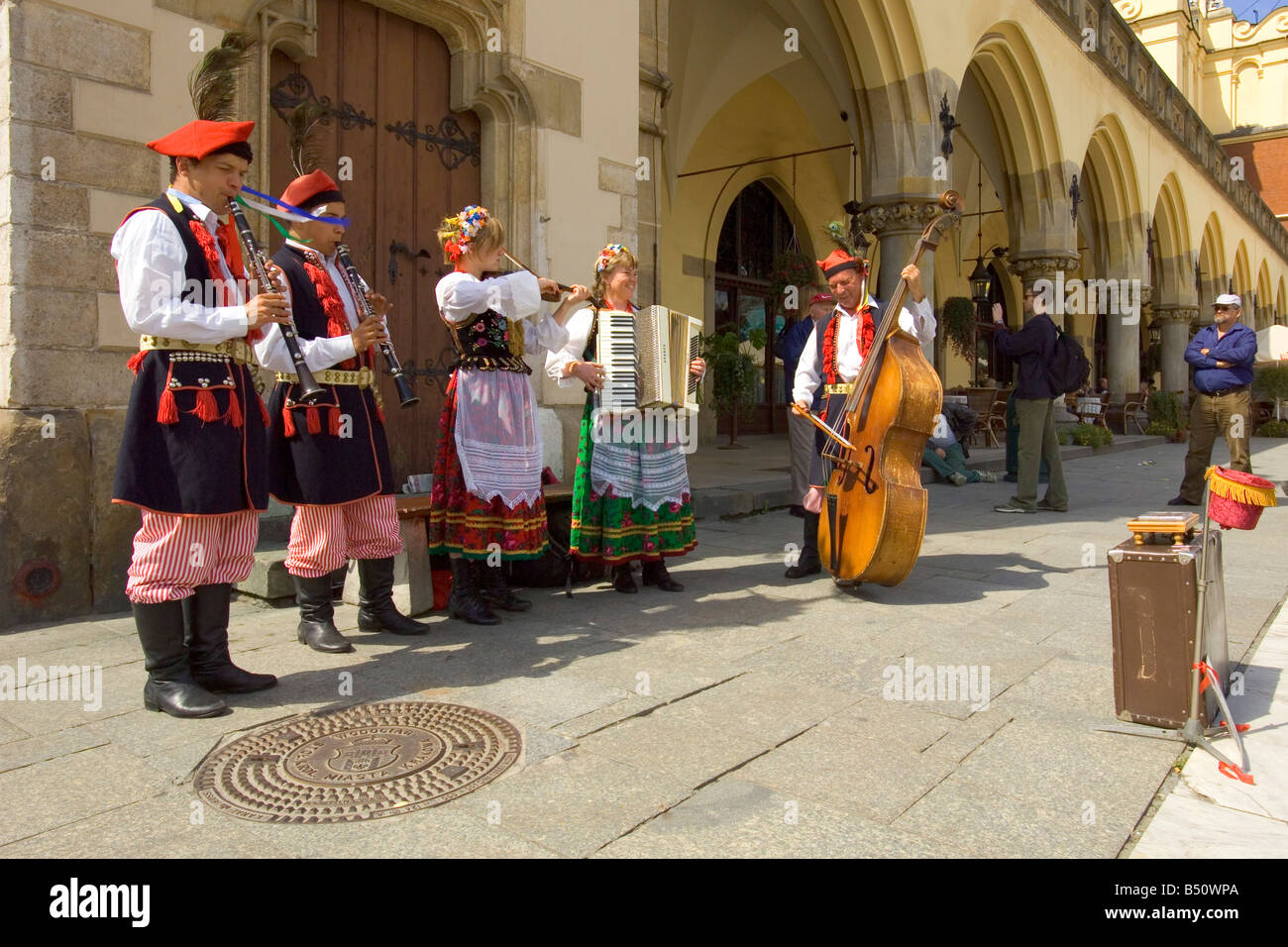 Street performers playing in the Main Market Square of Krakow with the Sukiennice Cloth Hall building behind them. Stock Photo