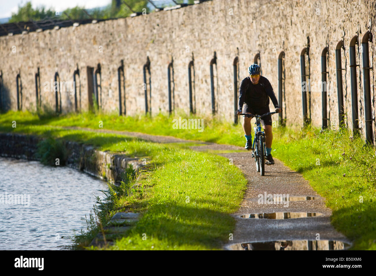 Cyclist riding along a canal towpath Stock Photo