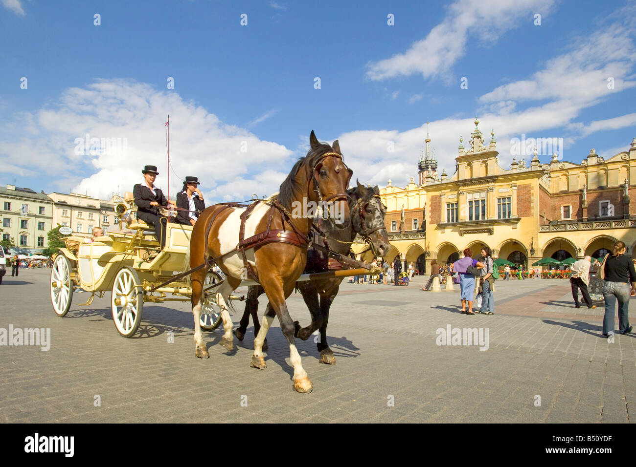 A tourist horse drawn carriage in the Main Market Square of Krakow in Poland with the Sukiennice Cloth Hall behind right. Stock Photo