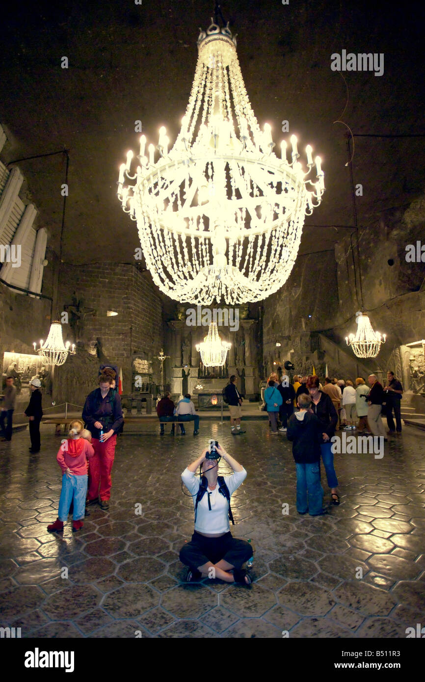 Tourists in St Kinga's Chapel of the Wieliczka Salt Mines in Krakow beneath a huge chandelier carved from rock salt. Stock Photo
