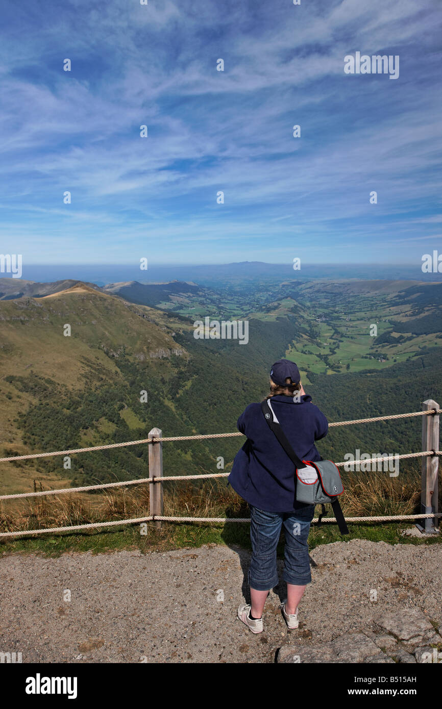 A tourist photographs the distant mountains from the Puy Mary, France Stock Photo