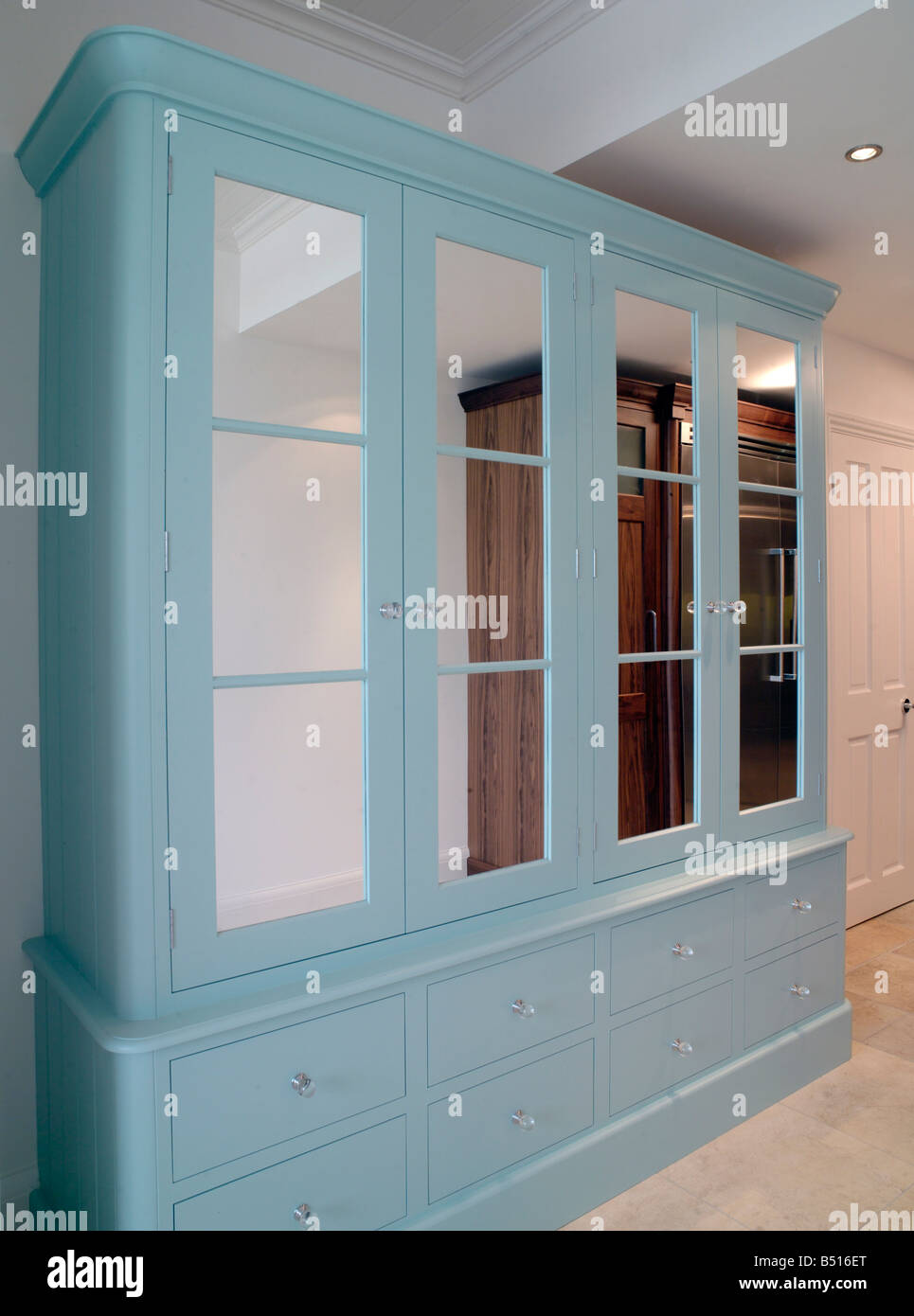 Kitchen or bedroom unit painted blue with mirror doors. Drawers below Stock Photo