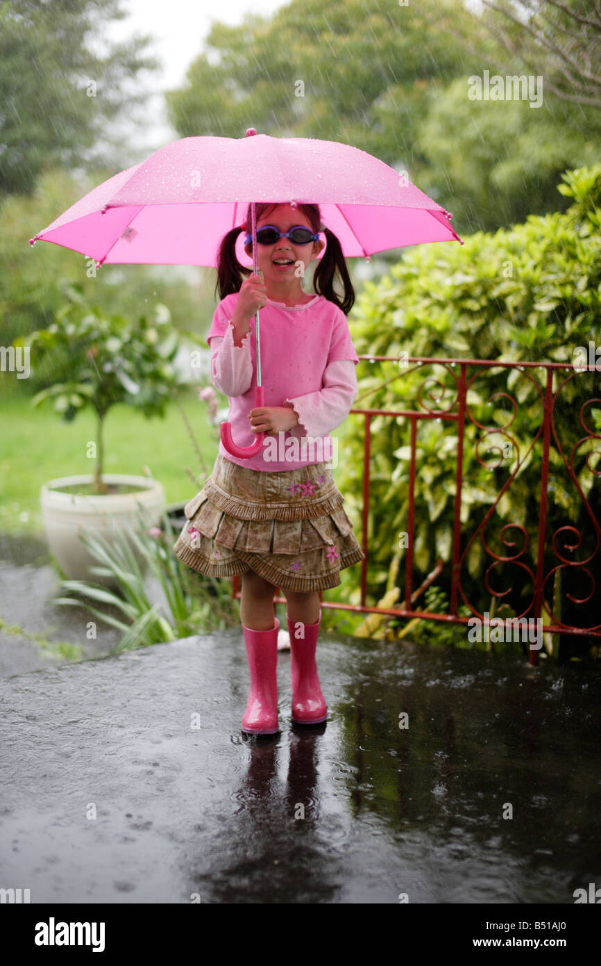 Girl in rain with pink umbrella five year old Stock Photo