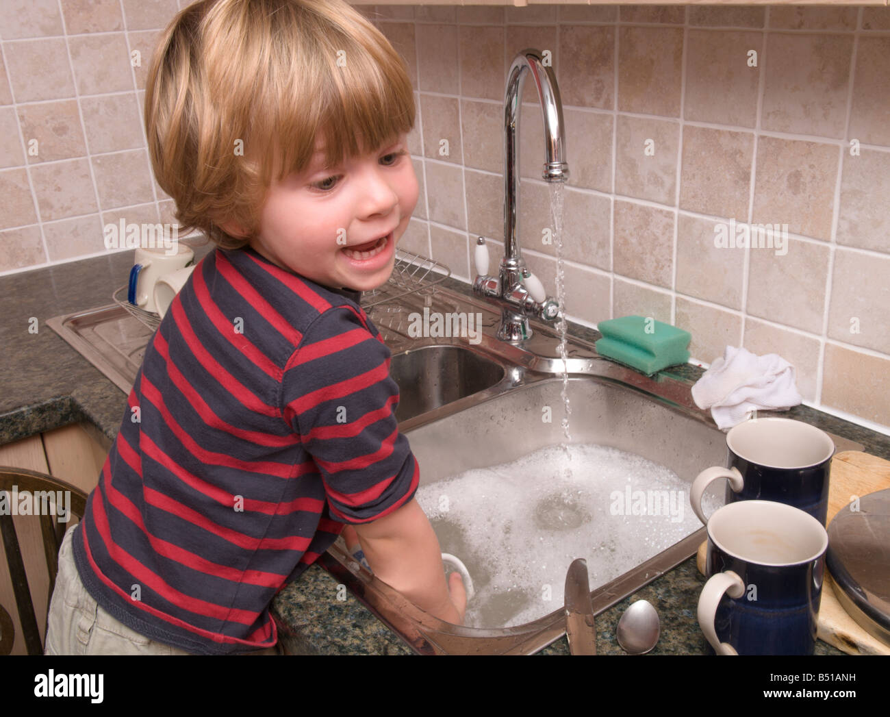 toddler boy child washingup kitchen sink doing the dishes with hot