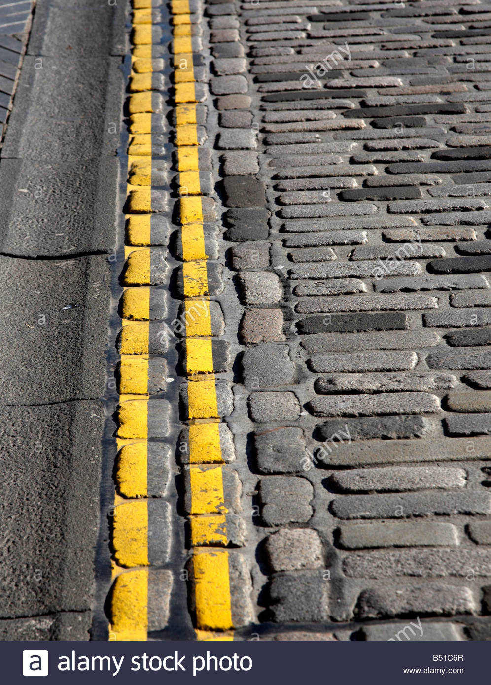 Double yellow lines on cobbled road Stock Photo