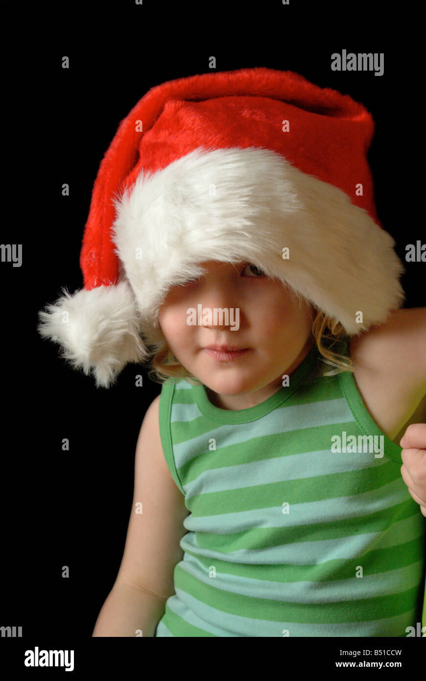 White girl wearing a red christmas hat and green stripy vest, looking apprehensive. Stock Photo