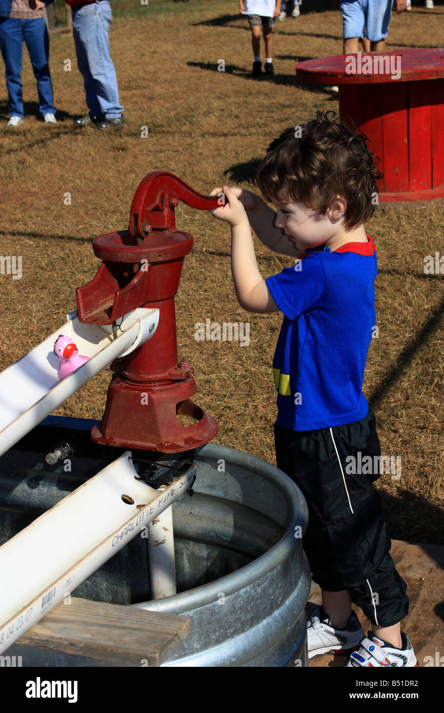 Child playing game with pump on farm.  Dixie, Louisiana, USA (Caddo Parish). Stock Photo