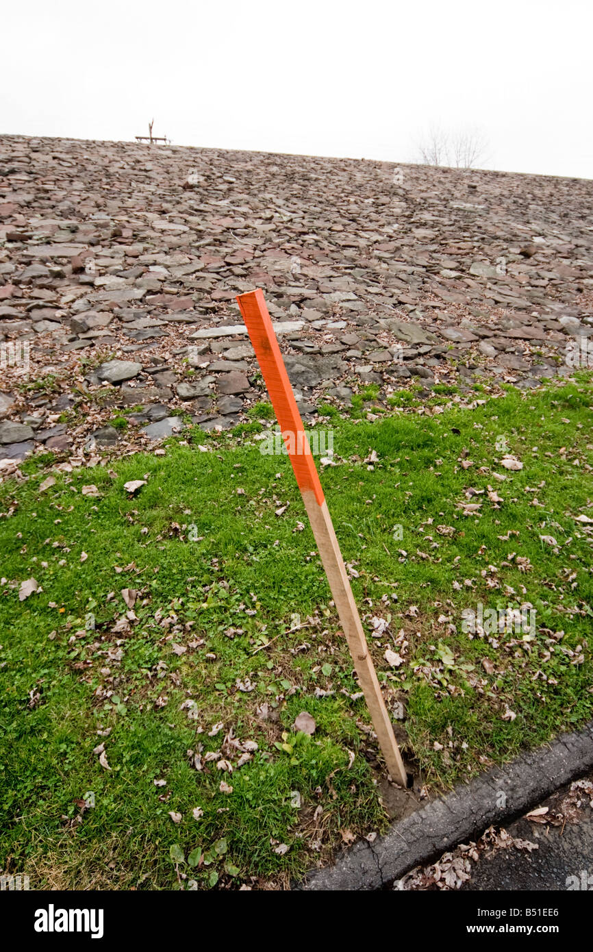 A wooden stake painted red on the top stuck into the ground Stock Photo