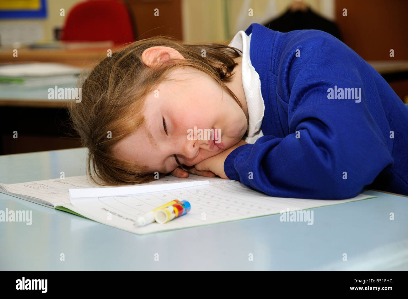 Schoolgirl asleep on her desk Pupil sleeping in school classroom Stock