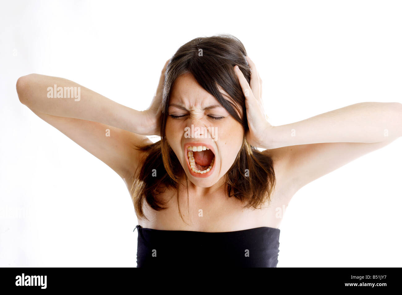 The young woman holds her head and screams Stock Photo