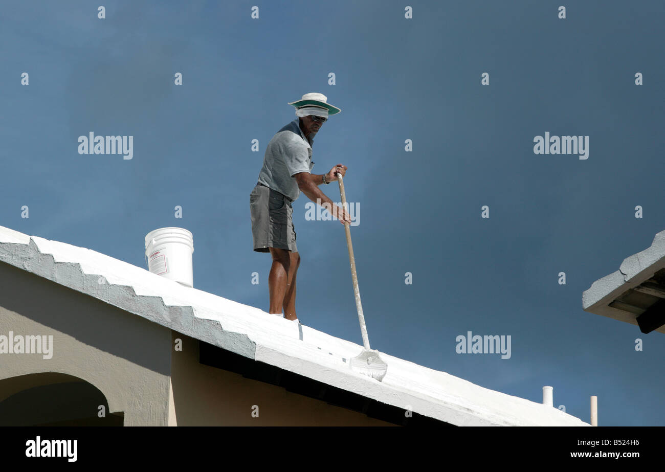 Close-up shot of Bermudan Man Limewashing a roof Stock Photo