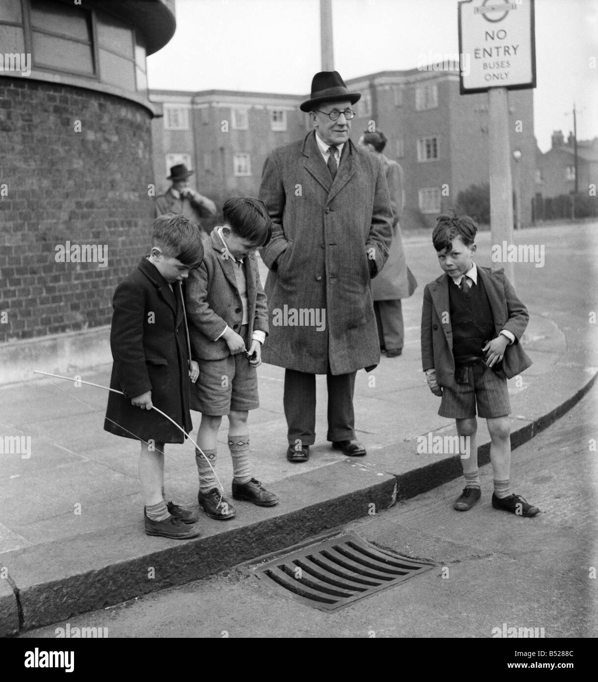 69 Years old Tommy Atkins of Palmers Green, North London, Keeps young by laughing-at his own jokes. Mr Atkins retired stage Ventriloquist spends odd moments throwing his voice down drains, behind looked doors, or inside large panels. Passers-by are amazed when they hear faint faraway cries of 'Let me out'. April 1953 D2163 Stock Photo