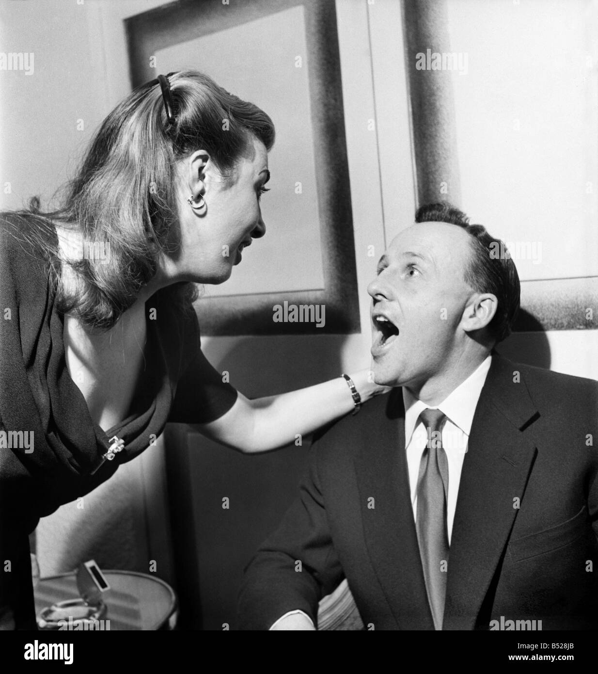 Jackie Buckland, one of his fans, examines Jimmy Young's golden dollar-earning tonsils. January 1953 &#13;&#10;D386-001 Stock Photo