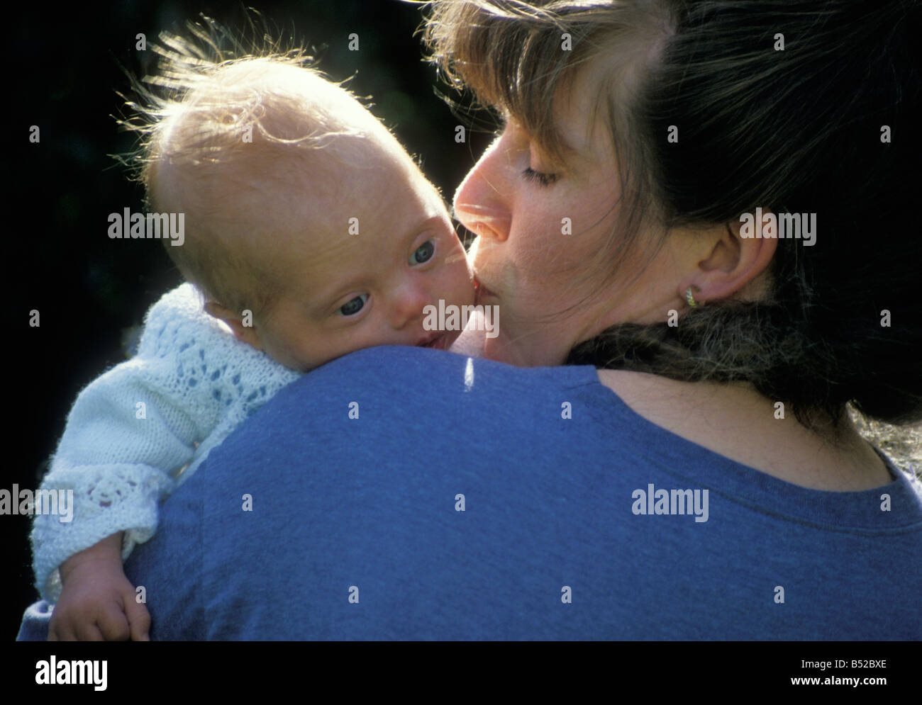 young mother cuddling her newborn downs syndrome baby Stock Photo