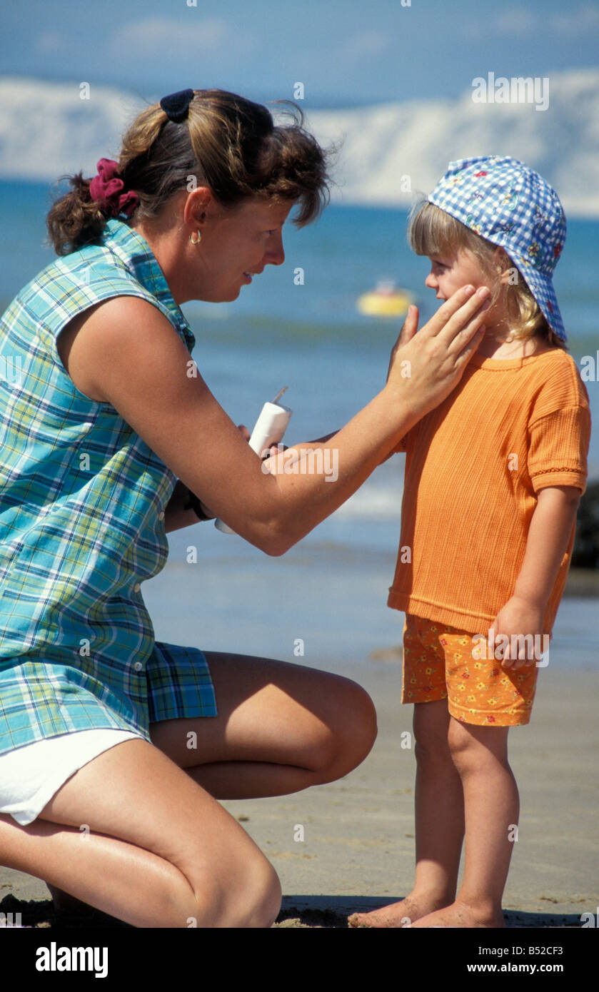 mother putting suntan lotion on little girl on beach Stock Photo Alamy