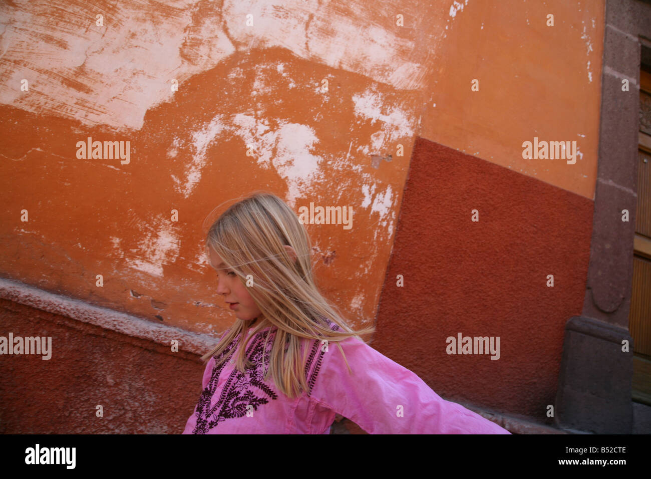 Eight year old Girl with long blond hair walking along street in San Miguel de Allende Mexico  Girl Strolling along outdoors Stock Photo