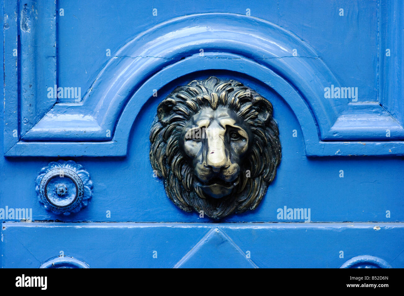 Bright blue front door with a brass decorative lion face Stock Photo
