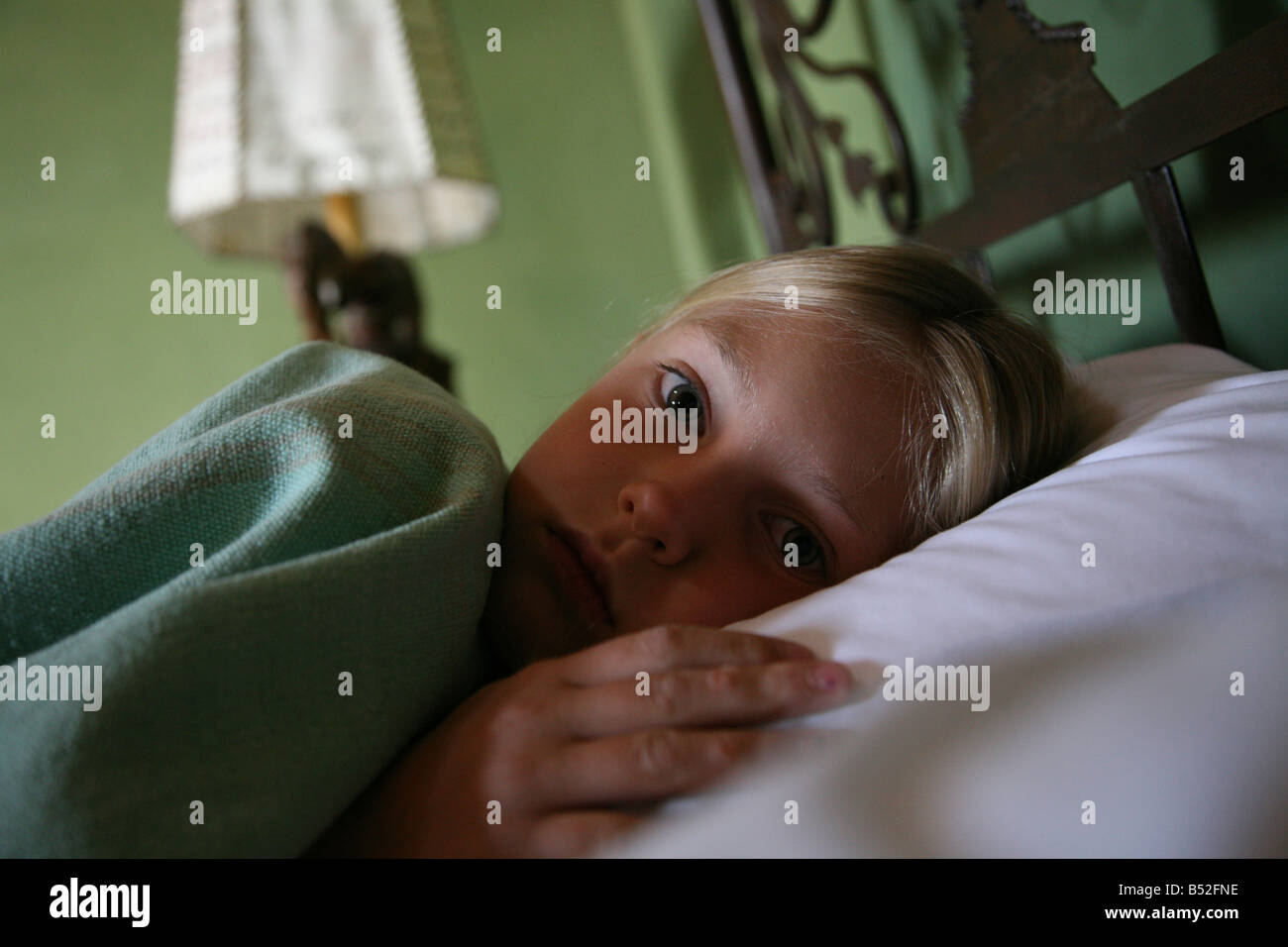 Eight year old girl lying down while recovering from stomach upset while traveling abroad Stock Photo